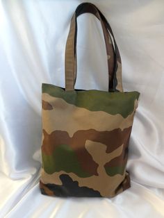 Medium size camo print unisex  book bag / Tote bag This striking tote / book bag features a 'camo' print in a premium canvas fabric. The camoflage print in khaki brown and black features on one side with the other side in a black waterproof canvas. The bag is lined in black cotton drill and has 3 interior pockets. Long handles attach to the bag in the same camo print. It has enough space to hold all essentials such as purse / wallet, phone, Ipad, bottle of water etc Also durable and functional a Khaki Rectangular Canvas Bag For School, Military Style Satchel Bag For Daily Use, Military Style Rectangular Travel Bag, Military Style Rectangular Bag For Everyday Use, Camouflage Tote Bag For Travel, Rectangular Camouflage Bag For Everyday Use, Military Style Canvas Bags For Everyday Use, Military Style Shoulder Bag For Everyday Use, Everyday Use Rectangular Camouflage Bag