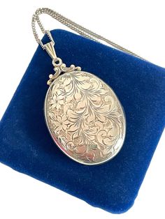 Description: Beautiful and large, the signature Birks style vintage oval locket, hand engraved with a whimsical swirling leaves and flower design, crowned with a fancy filigree top.  The sterling silver pendant opens easily and holds two oval areas for photos.  The design is on the front of the locket.  The back has a monogram engraving. It reads "IH" in cursive (open for interpretation - could also be JH or TH).   The locket hangs from a triangular grooved bail.  Hangs on a lovely, long and shiny silver link chain (24'' long). The photo frames are intact and in very good vintage condition.  Measures:  Chain: Approx. 22'' long. Locket (Oval Only): 1 7/8'' (Includes fancy filigree top) and 1 3/16'' wide. Weighs:   - 22.1 grams (locket with chain) Condition: In nice vintage condition.  Clasp