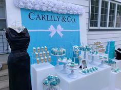 a table topped with cakes and cupcakes next to a sign that says carlly & co