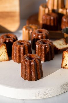 several bundt cakes sitting on top of a white cake plate next to other desserts