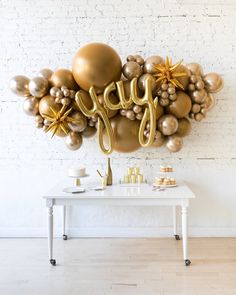 a white table topped with balloons and gold stars next to a wall that says joy