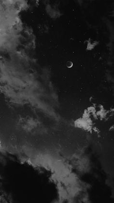 black and white photograph of the moon in the sky with clouds around it at night