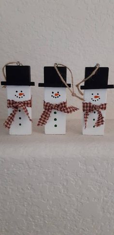 three snowmen wearing hats and scarfs are standing next to each other on a white surface