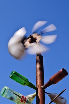 a wind spiner that has several empty bottles attached to it and is spinning in the air