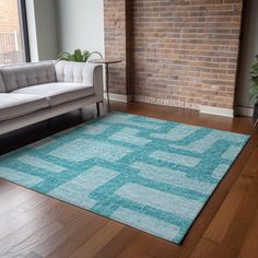 a living room with a couch, chair and rug in front of a brick wall