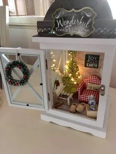 two small windows with christmas decorations in them on a table next to a potted plant