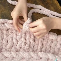 a woman is crocheting a blanket with her hands on the end of it