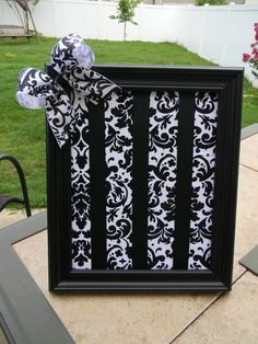 a black and white photo frame with a bow on the top, sitting in front of a lawn