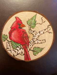 a red bird sitting on top of a tree slice