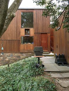 a house that is next to a tree and some bushes on the side of it