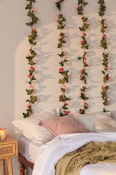 a bed with white sheets and pink flowers on the wall above it, next to a night stand