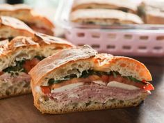 a cut in half sandwich sitting on top of a wooden table next to a container