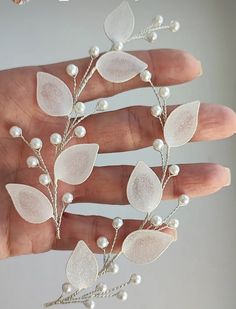 a woman's hand is holding some white flowers and pearls