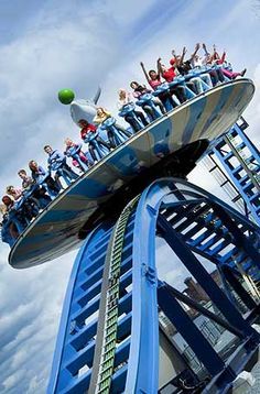 people are riding the roller coaster at an amusement park