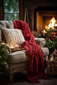 a chair with a blanket on it next to a fire place and christmas tree in the background