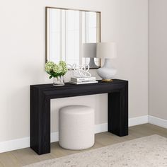 a white vase sitting on top of a wooden table next to a mirror and lamp