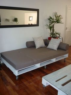 a living room with a couch, mirror and coffee table on the floor in front of it