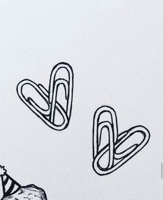 two paper clips with hats on them sitting next to each other