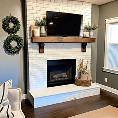 a living room with a white brick fireplace and tv on top of the mantel