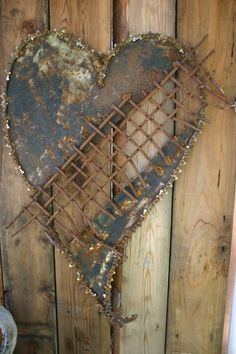 an old rusty heart hanging on a wooden wall