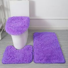 two purple rugs and a toilet in a bathroom