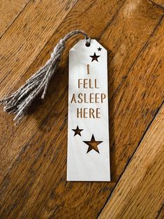 a tag that says i fell asleep here on a wooden floor with tassels