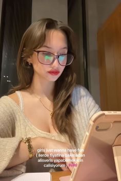 a woman wearing glasses is looking at her laptop