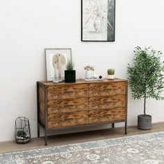 a wooden dresser sitting next to a potted plant on top of a hard wood floor