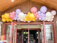 balloons and streamers are hanging over the entrance to a building that is decorated for a party