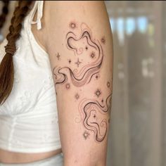 a woman's arm with a tattoo on it that has stars and clouds in the sky