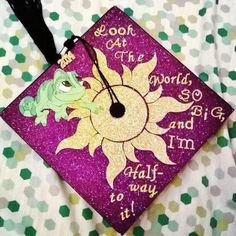 a purple and yellow graduation cap with the words look at the world, go and half way to it