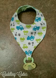 a baby bib with a pacifier attached to it's side on a tile floor