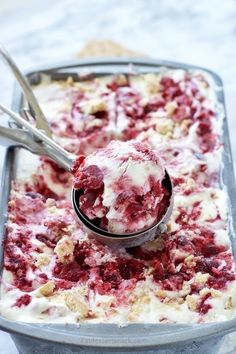 a scoop of ice cream with raspberry topping in a metal pan on a table