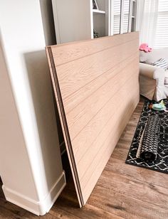 there is a wooden headboard on the floor next to a white couch and window