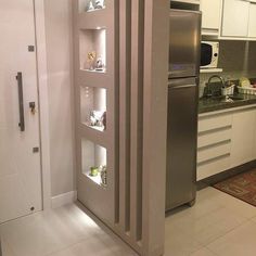 a stainless steel refrigerator in a kitchen with white cupboards and drawers on the wall