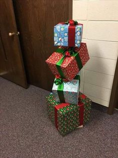 several wrapped presents stacked on top of each other in front of a door with christmas decorations