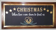 a christmas sign hanging from the side of a wall next to a wooden framed frame