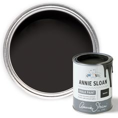 an open can of black chalk paint next to a white tin with the word annie sloan on it