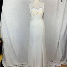 a white dress is on display in front of a wall with clothes hanging from it