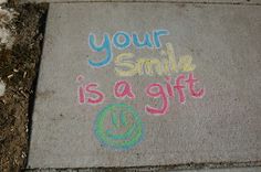 a sidewalk with chalk writing on it that says your smile is a gift