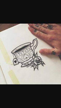 a drawing of a tea cup with roses on it and a person's hand next to it