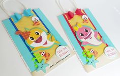 two little bags with tags on them that say happy birthday and have shark decorations hanging from the handles