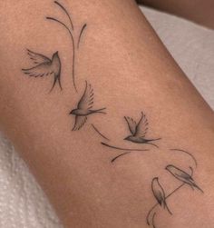 a woman's arm with three birds flying in the air and one bird on it