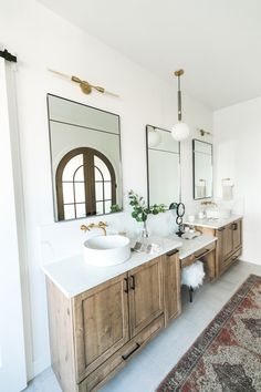 a bathroom with two sinks, mirrors and rugs on the floor in front of them