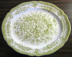 a green and white plate with flowers on it sitting on top of a wooden table