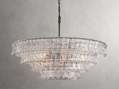 a glass chandelier hanging from the ceiling in a room with grey walls and flooring