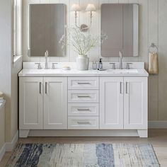 a bathroom with two sinks, mirrors and rugs on the floor in front of it