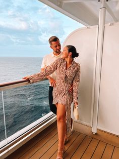 a man and woman standing on the deck of a cruise ship looking at each other