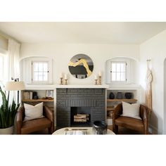 a living room filled with furniture and a fire place in front of a clock on the wall