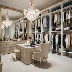 an organized closet with chandelier, dressing table and chair in front of it